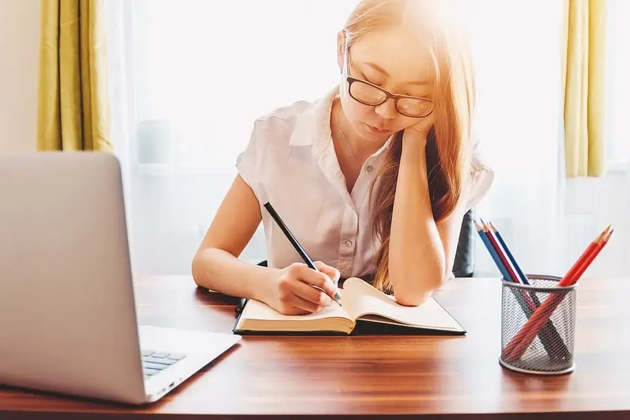 Girl with glasses writing down in notebook