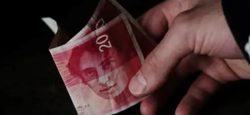 A person holding a 20 Israeli new shekel banknote-min