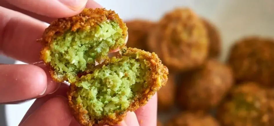 A person showing the inside of a fried falafel