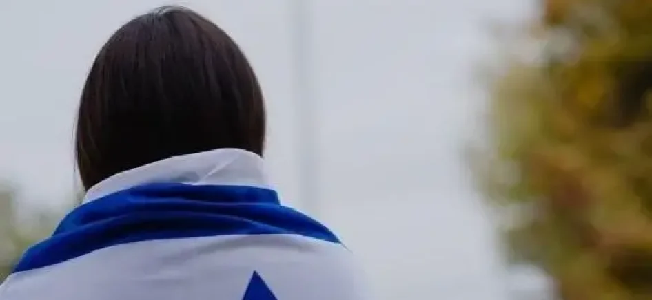 A person with an Israeli flag wrapped around his back