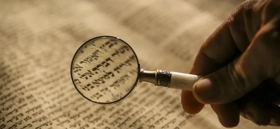 a person reading Hebrew through a magnifying glass