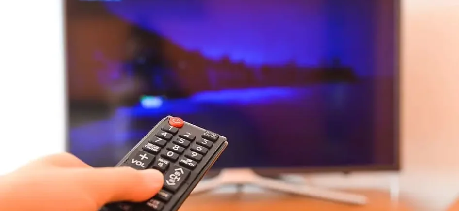 Person turning the TV on with remote control.