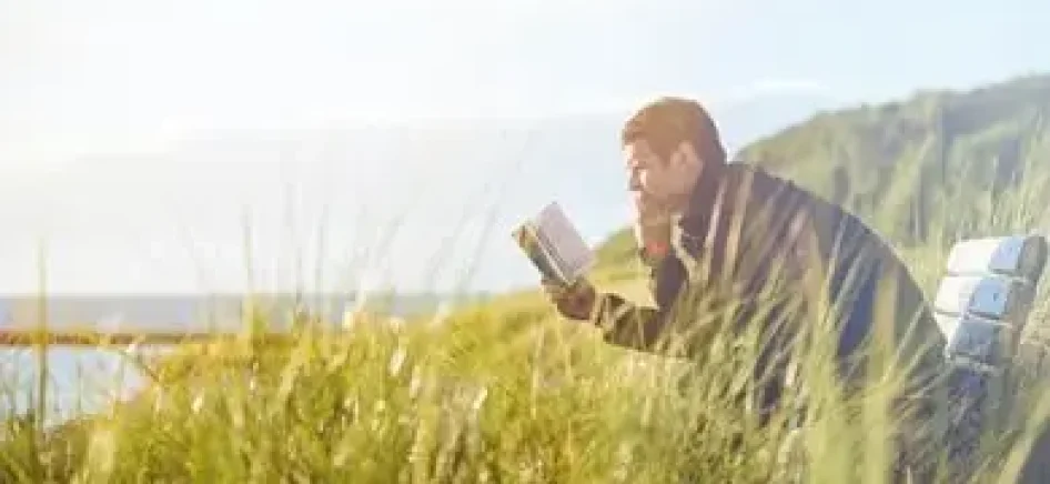 Man reading a book in the field